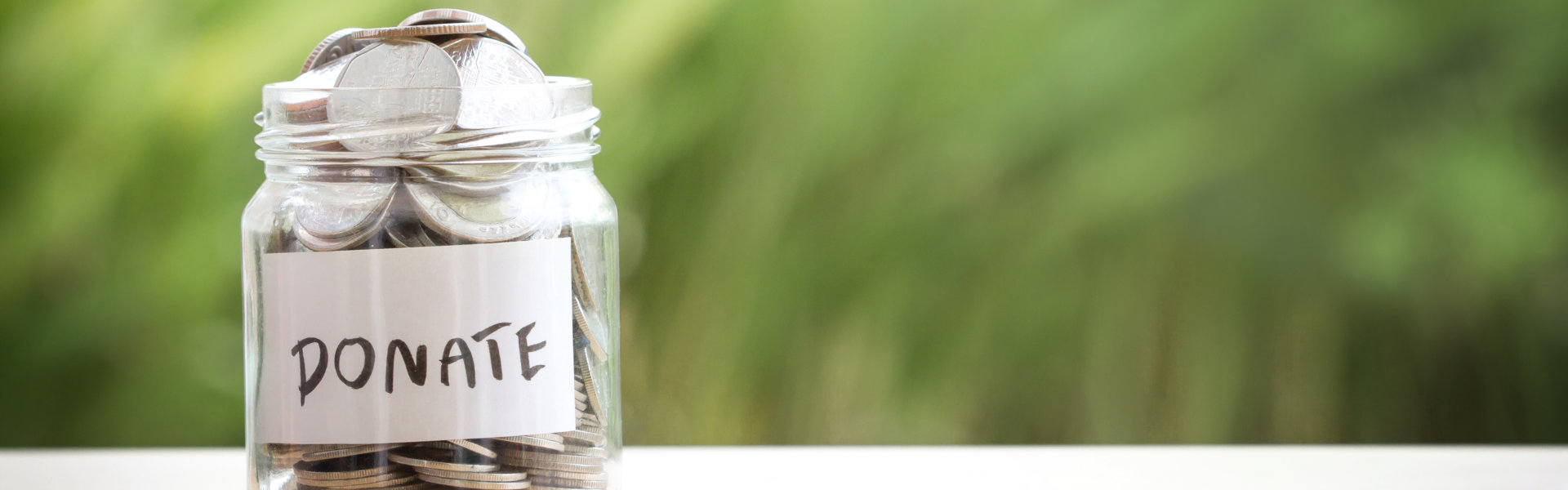 Hand putting Coins in glass jar for giving and donation concept